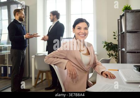 Happy businesswoman at desk in bright office, confident professional portrait Stock Photo
