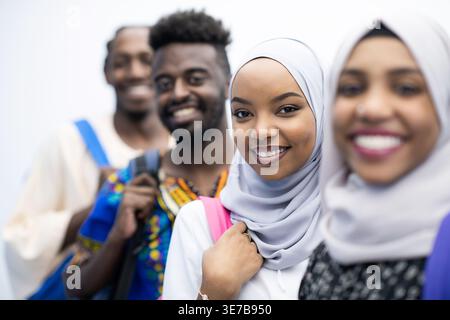 Smiling Black and Muslim college students standing with backpacks against white background in studio Stock Photo