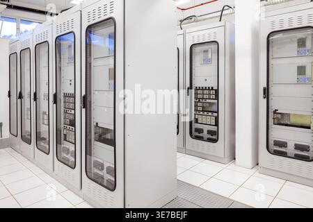 A clean and organized electric room features rows of specialized control panels and protection relay cabinets in an electrical substation. Stock Photo