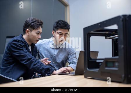 Chinese male IT experts using 3D printer in office Stock Photo