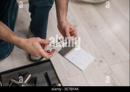 A plumber is replacing a faucet in the kitchen. Stock Photo