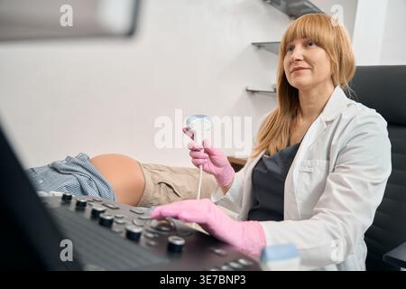 Caucasian woman operating ultrasound machine in medical room Stock Photo