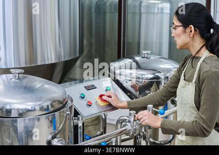 Mixed race woman operating machinery standing in factory Stock Photo