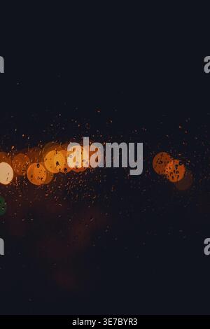 Rain drop on window at night. Outside window is blurred bokeh of raining city light Stock Photo