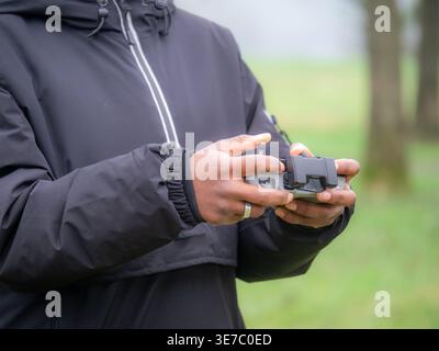 Young Black female with dreadlocks controlling drone while standing in park during daytime Stock Photo