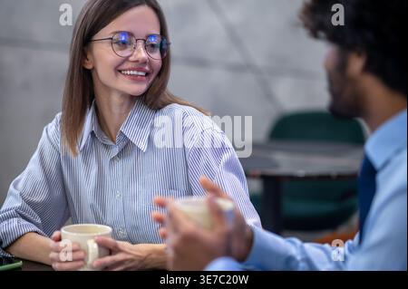 Indian businessman talking to female colleagues having coffee sitting at table in restaurant Stock Photo