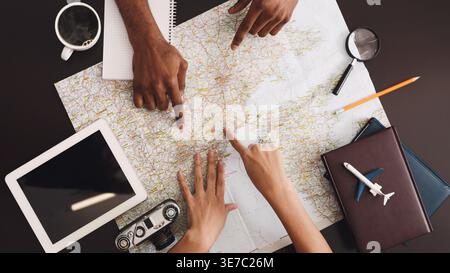 Black couple pointing on map planning vacation trip at home Stock Photo