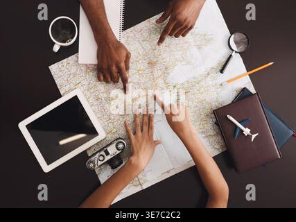 Black couple pointing on map planning vacation trip at home Stock Photo