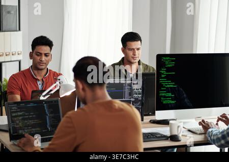 Indian male web developers writing codes for new computer program in IT office Stock Photo