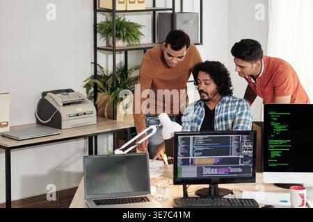 Indian male web developers writing codes for new computer program in IT office Stock Photo