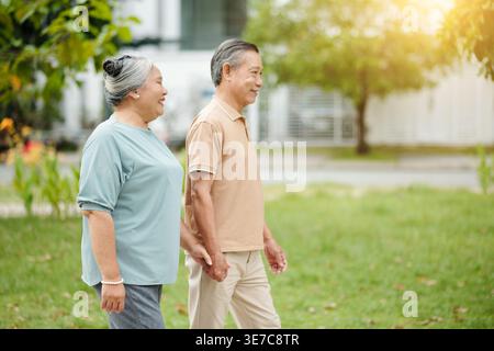 Senior Asian couple holding hands while walking on park Stock Photo