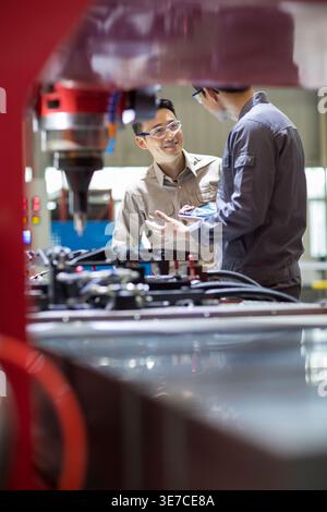 Chinese male engineers checking machine in factory Stock Photo