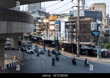 Bangkok Thailand January 16 2026. Cars motorcycles and small shops appear beside an elevated road and curved intersection near Khlong Toei Market. Stock Photo