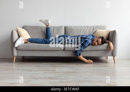 Tired Middle Eastern man sleeping while lying on sofa in living room at home Stock Photo