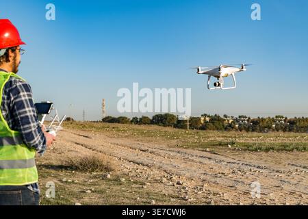 Drone operated by Middle Eastern male construction worker standing on construction site during daytime Stock Photo