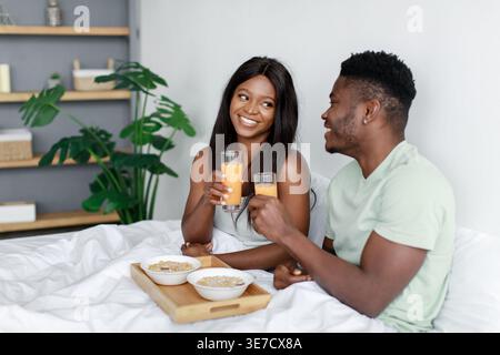 Black couple having breakfast while sitting on bed in bedroom at home Stock Photo