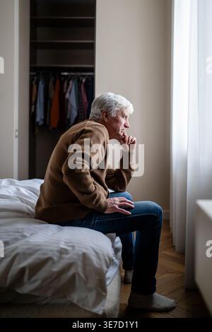 Senior man alone at home with hand over mouth reflecting in fear and apathy. Dementia sick issues Stock Photo