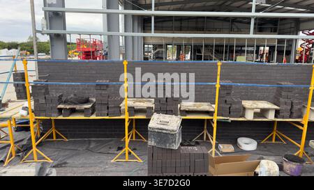 Brick stacks on yellow scaffolds near a partially built structure. Stock Photo