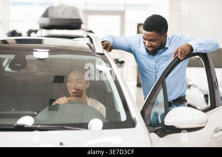 Black man standing beside car looking at wife sitting in driver seat of car Stock Photo