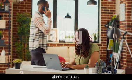 Young freelancer working remotely from home, analyzing online information to plan accounting sales report. Using financial data on internet to send email, startup company job. Tripod shot. Stock Photo