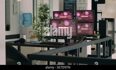 IT office with multiple monitors showing critical error message flashing on screens, hacking attack alert. Empty desk with computers displaying system crash and network security breach. Stock Photo