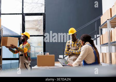 African american warehouse managers discussing pick ticket on laptop. All black ecommerce retail storehouse employees working in storage room and preparing buyer order for dipatching Stock Photo