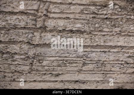 Close-up of a natural limestone wall in a stone quarry featuring distinct horizontal parallel lines and rough texture from industrial cutting equipmen Stock Photo
