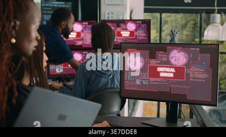 Team of system engineers having web server hacked, reading critical error on multiple monitors in office. Diverse software developers trying to solve hacking problem, firewall security. Stock Photo