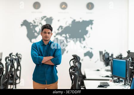Middle Eastern businessman standing with crossed arms near computers in office Stock Photo