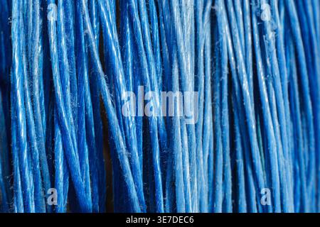 Macro shot of bright blue synthetic bristles or textile threads creating a rhythmic linear pattern. Minimalist background with copy space and vertical Stock Photo