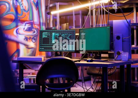 Malicious software on computer screen hacking server in abandoned warehouse at night time. Ransomware stealing information and breaking into database on monitor in hackers hideout Stock Photo