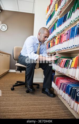 Middle Eastern male dentist sitting looking through file folders in dental office Stock Photo