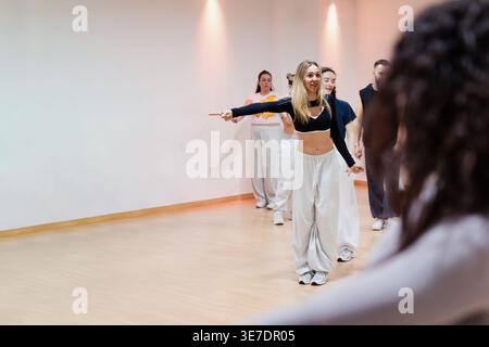 Female instructor leading dance class with students in studio Stock Photo