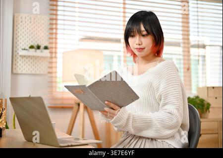 Beautiful Asian woman focusing on reading a book Stock Photo