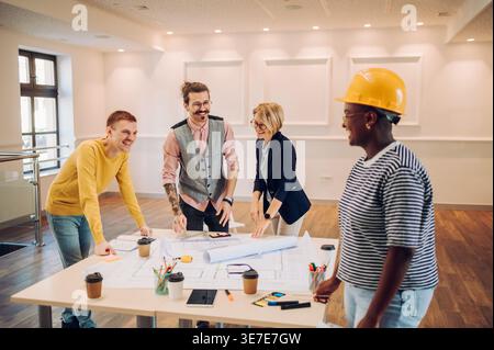 Cheerful Black woman laughing with caucasian colleague while working on the table in the office Stock Photo