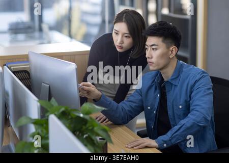 Chinese male and female IT experts working together on computer in office Stock Photo