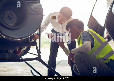 Chinese airplane mechanic checking helicopter with his apprentice in airport Stock Photo