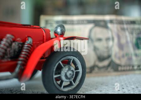 Small red model car on top of a financial stock market chart with a calculator, illustrating the data, costs, and analysis of investing in vintage aut Stock Photo