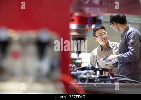 Chinese male engineers checking machine in factory Stock Photo