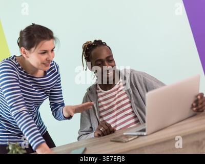 Smiling Black businessman sitting at table and looking at laptop working together with caucasian female colleague in the office Stock Photo