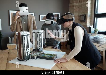 Group of architects wearing VR headsets standing around the table in office Stock Photo