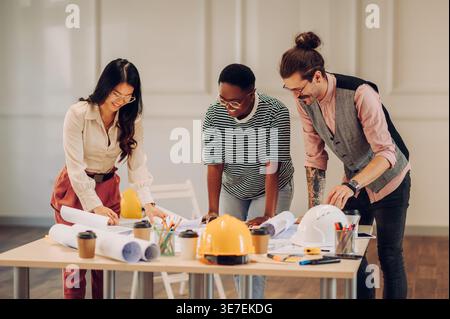 Cheerful Black and Asian woman with caucasian male college working on the table in the office Stock Photo