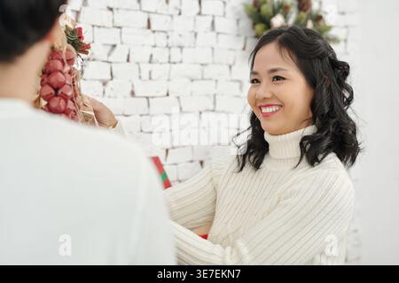 Vietnamese couple having fun decorating wooden Christmas tree at home Stock Photo