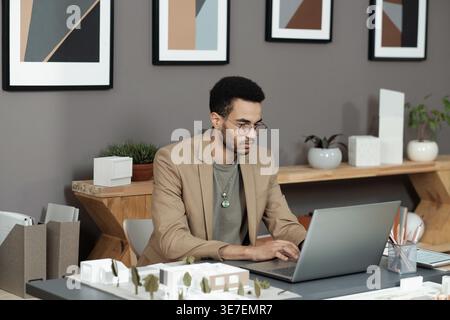 Serious mixed race man working on laptop in office Stock Photo