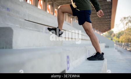 Cropped image of Thai man in fitness wear running upstairs in stadium on sunny day Stock Photo