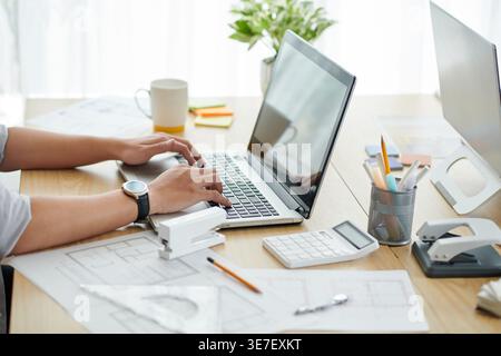 Hands of Asian male construction engineer working on laptop sitting at desk in office Stock Photo