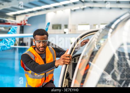 African American male aircraft engineer inspecting small plane in hangar Stock Photo
