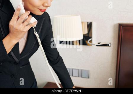 Cropped image of Asian female manager making phone call to request room service from hotel room Stock Photo
