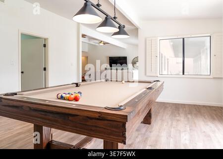 Rustic style solid wood pool table in spacious home game room with modern lighting window Stock Photo