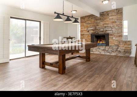 Rustic style solid wood pool table in spacious home game room with stone fireplace modern lighting Stock Photo